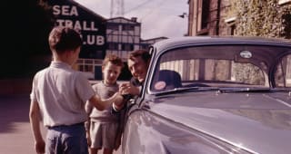 Jimmy Greaves pictured signing autographs for two young boys from the window of his Jaguar Mark 2 car outside Stamford Bridge, in 1965. 