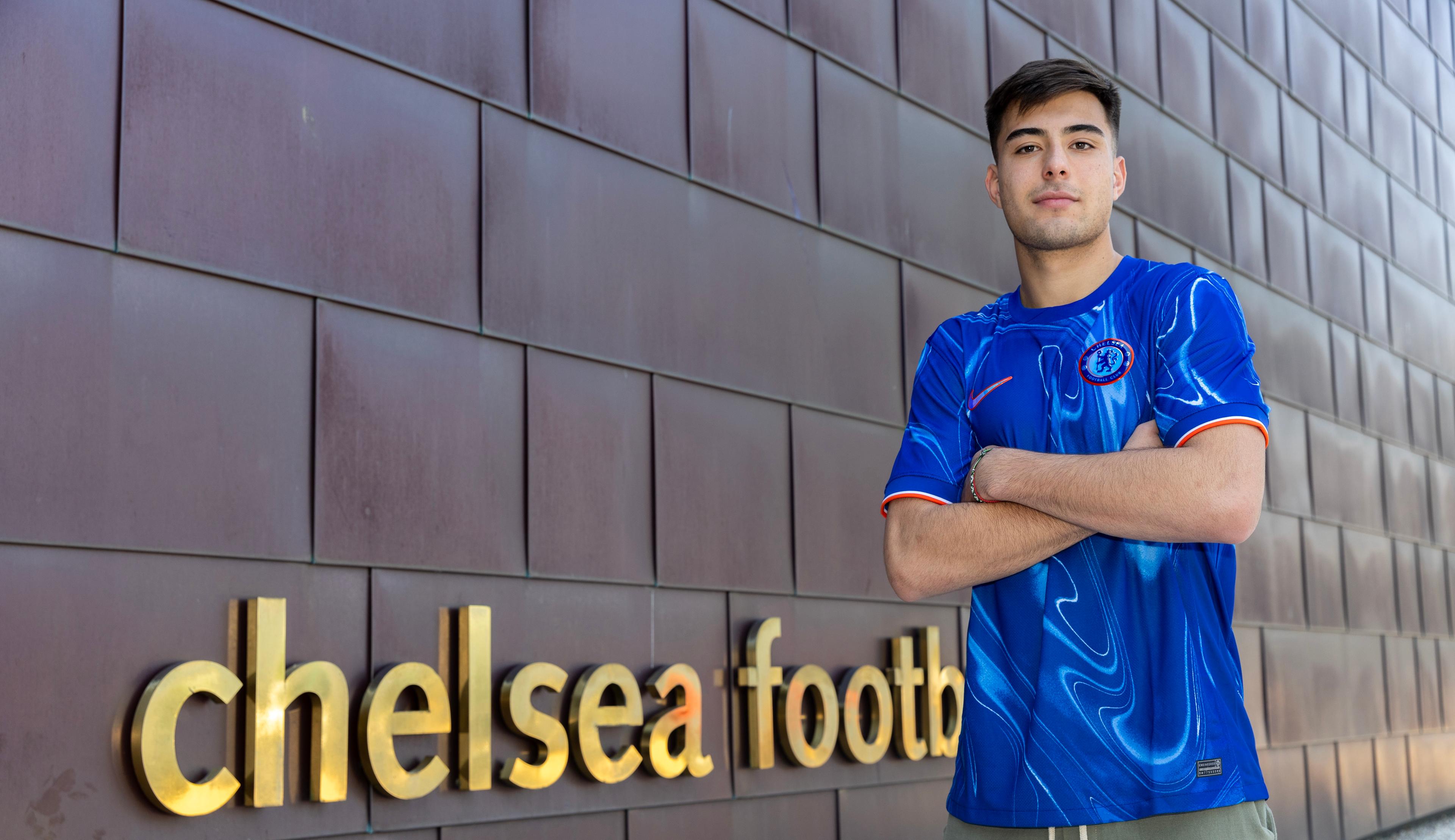 Aarón Anselmino poses in a Chelsea shirt outside the club building at Cobham