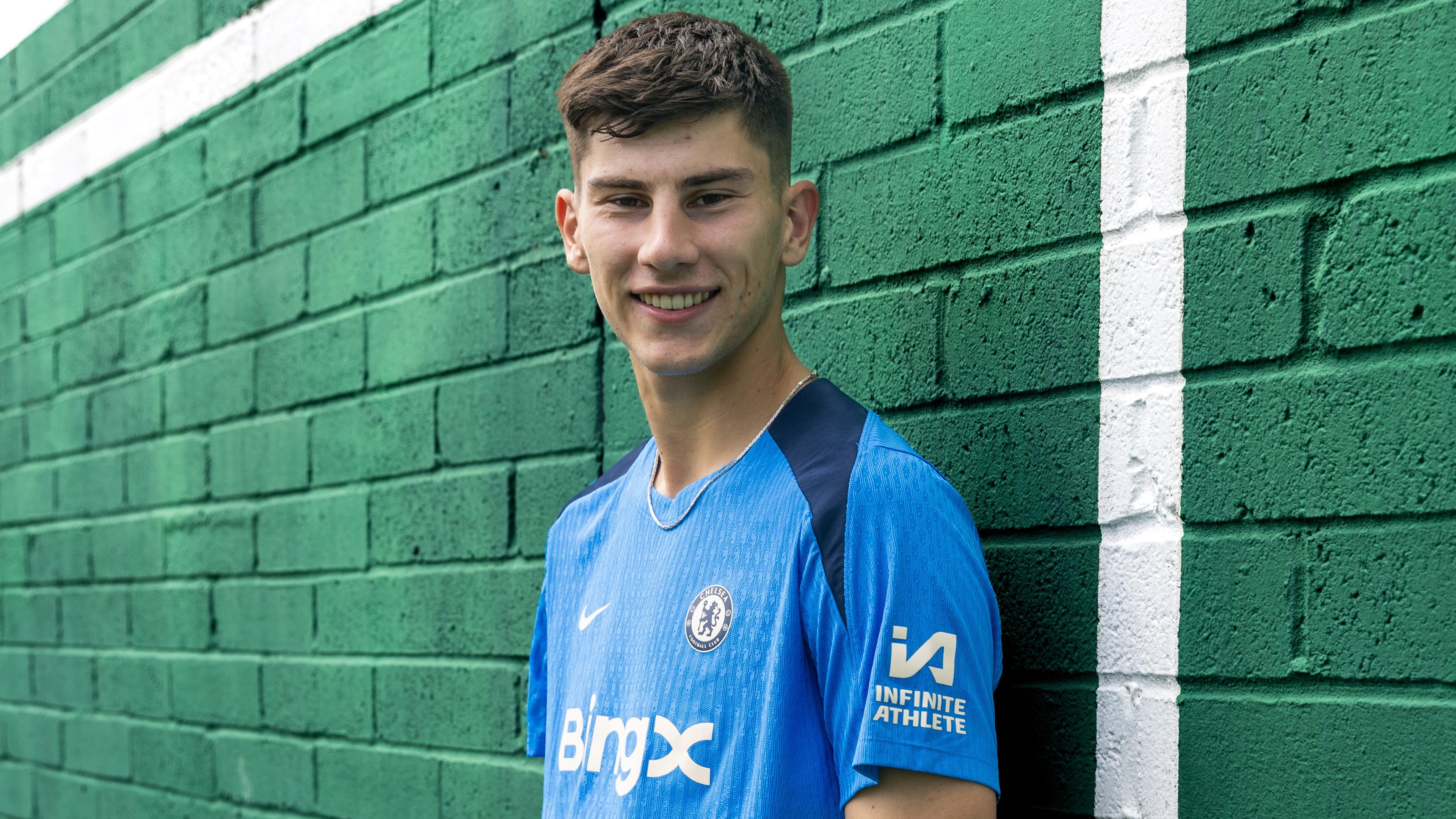 Mike Penders poses against a green brick wall during his Chelsea signing shoot