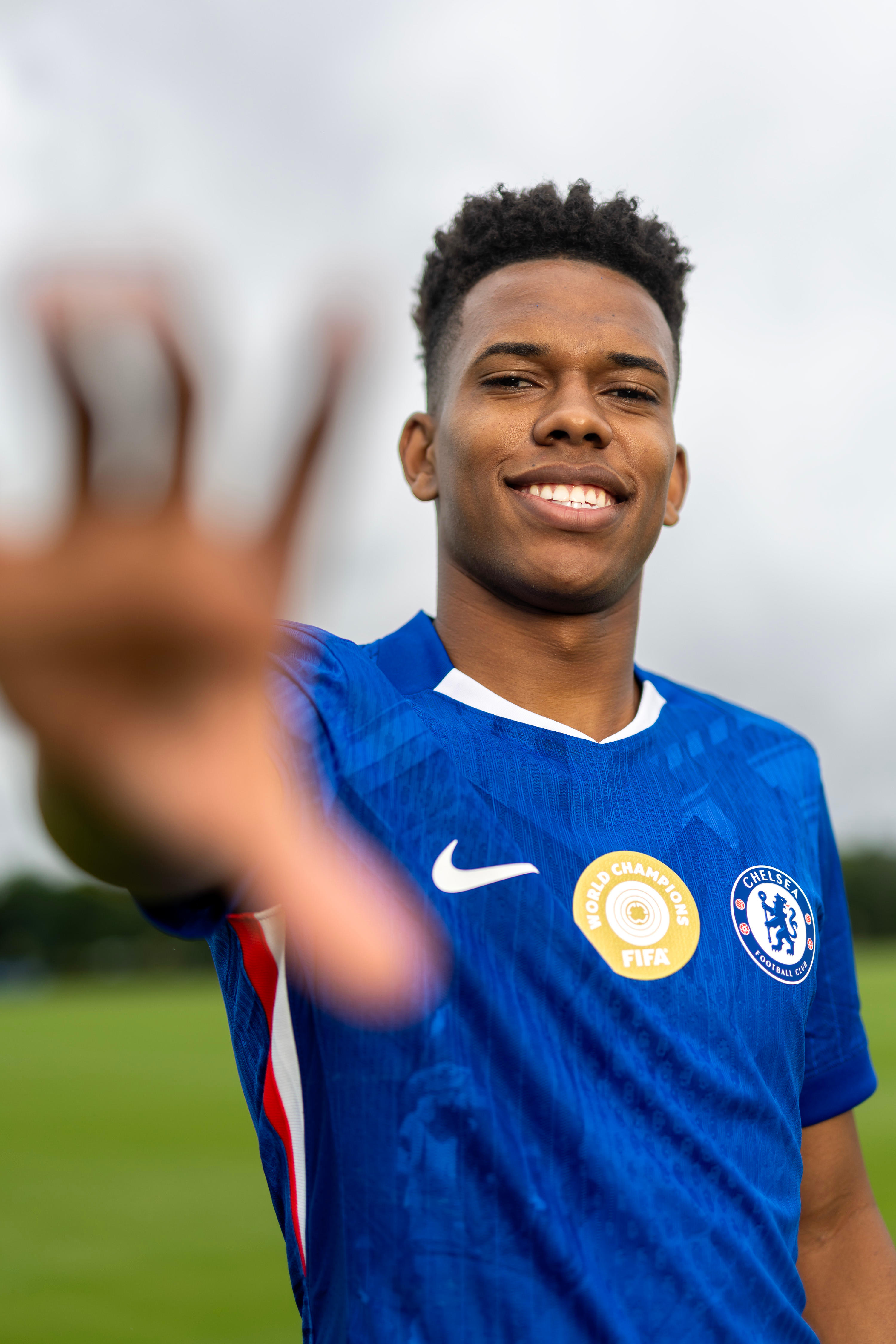 Estêvão reaches toward the camera in Chelsea kit during his arrival shoot