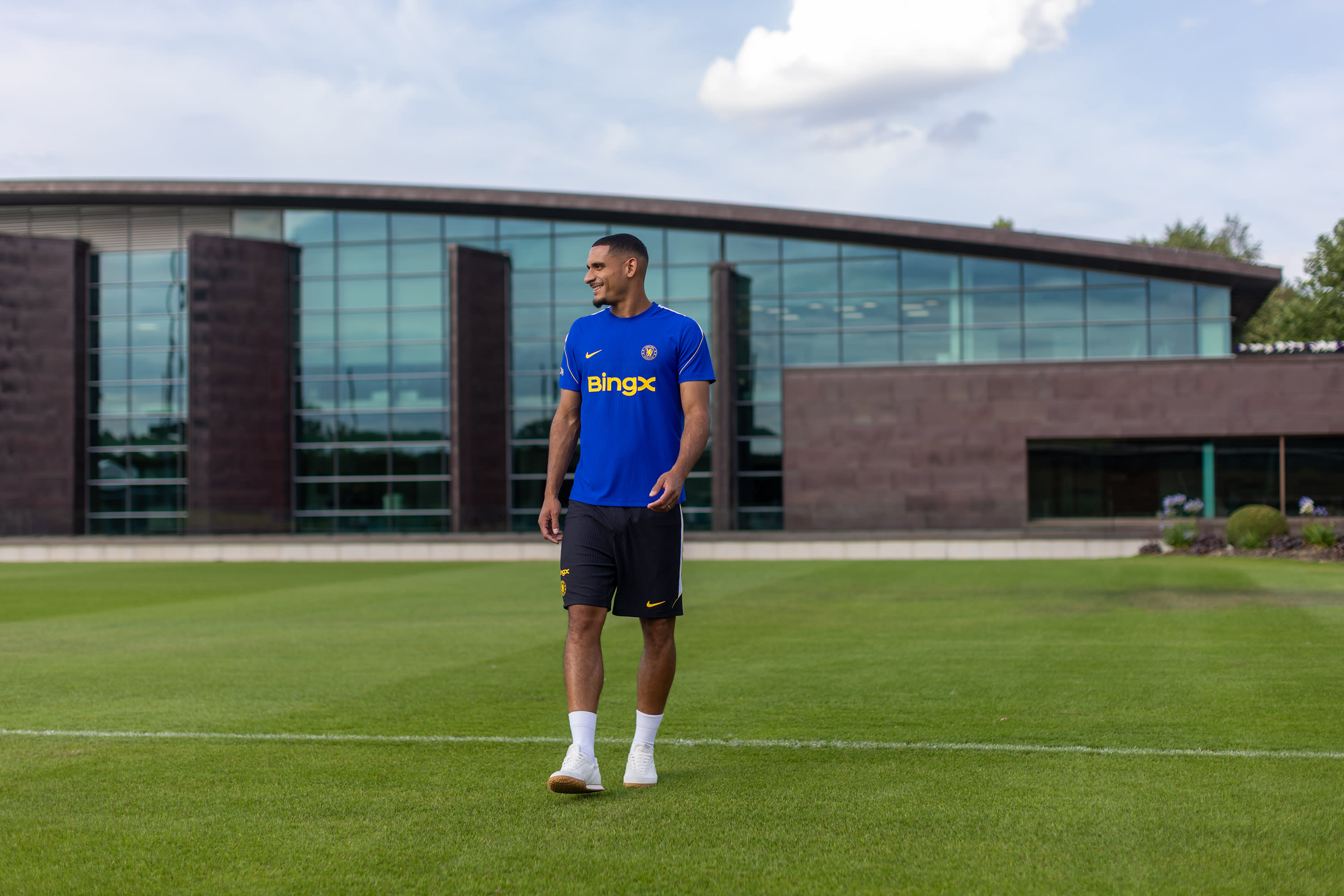 Maxence Lacroix stands on a Cobham pitch in Chelsea training kit on signing day