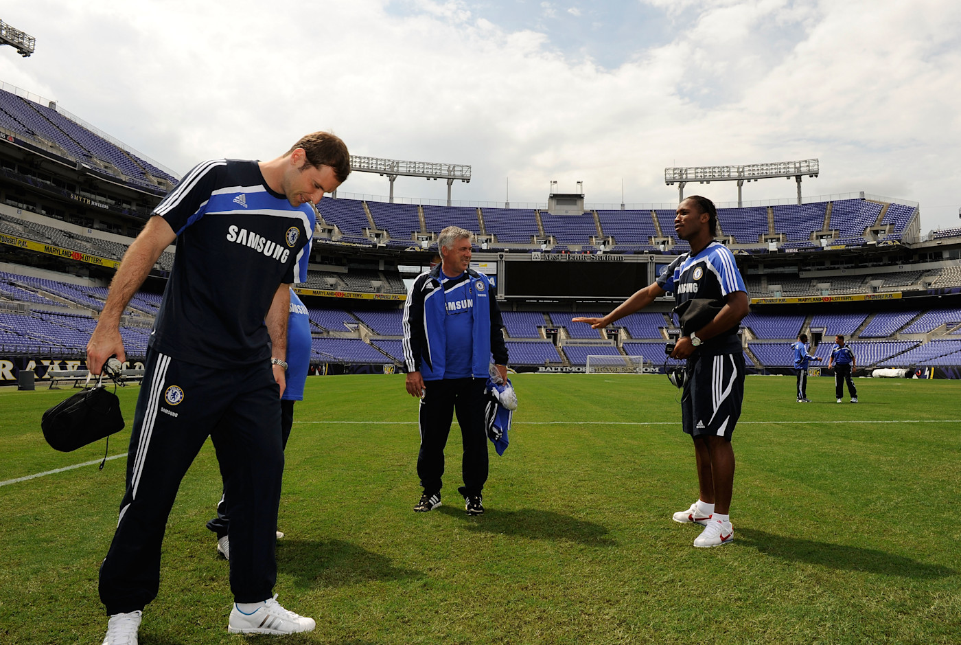 Petr Cech inspects the surface at the M&T Bank Stadium on the eve of the game as Ancelotti and Drogba share a joke